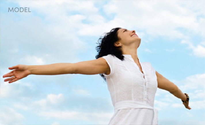 Joyous Woman Holding Her Arms Out and Looking Up at the Clouds