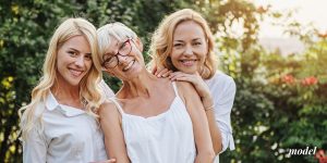 Mom with two daughters smiling outdoors