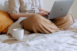 Person at home on their computer with a cup of coffee.